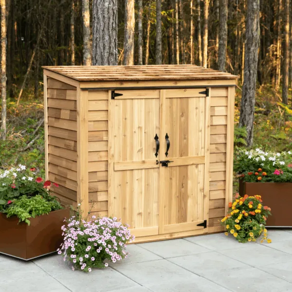 Wooden shed surrounded by colorful flowers.