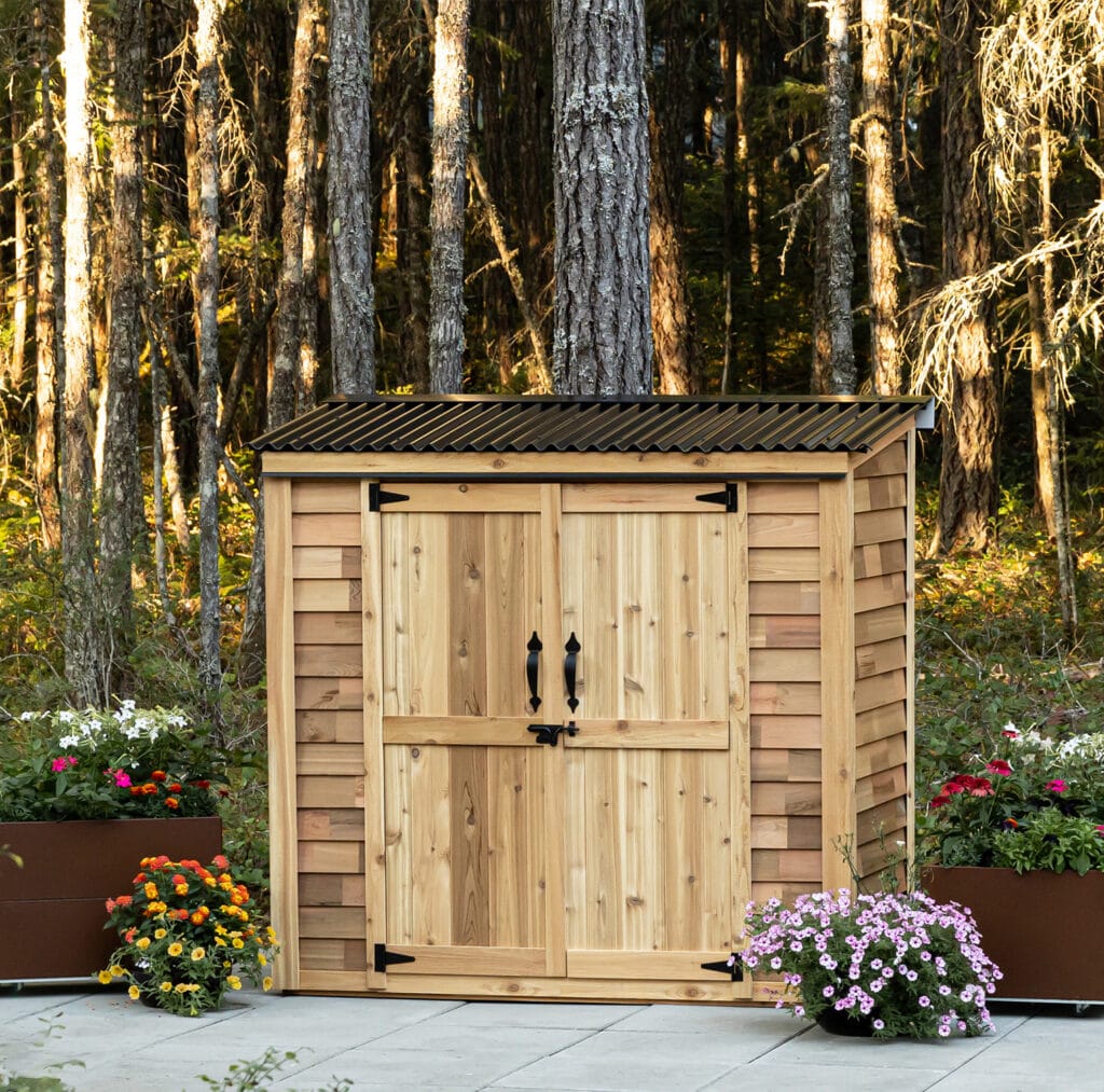 Wooden shed surrounded by colorful flowers.