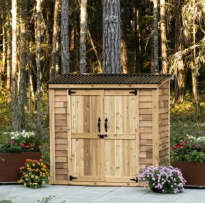 Wooden shed surrounded by colorful flowers.