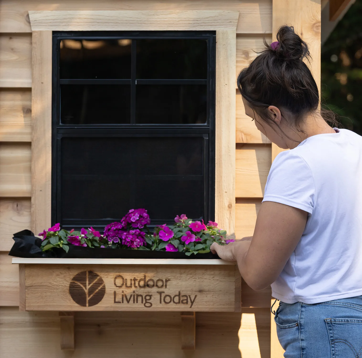 Woman tending flowers at window box.