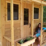 Wooden playhouse with potted plants.