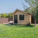 Wooden shed in green backyard setting.