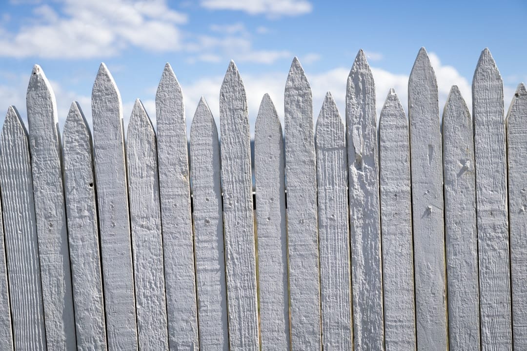 a white picket fence with a blue sky in the background