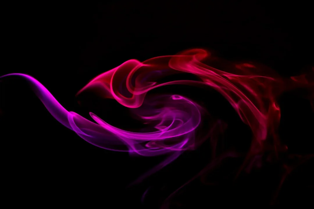 Photo by MARIOLA GROBELSKA a red and pink smoke swirl on a black background