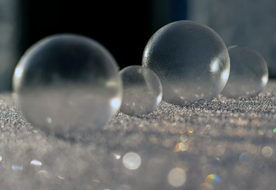Photo by Jonathan Cosens Photography a group of glass balls sitting on top of a sandy ground